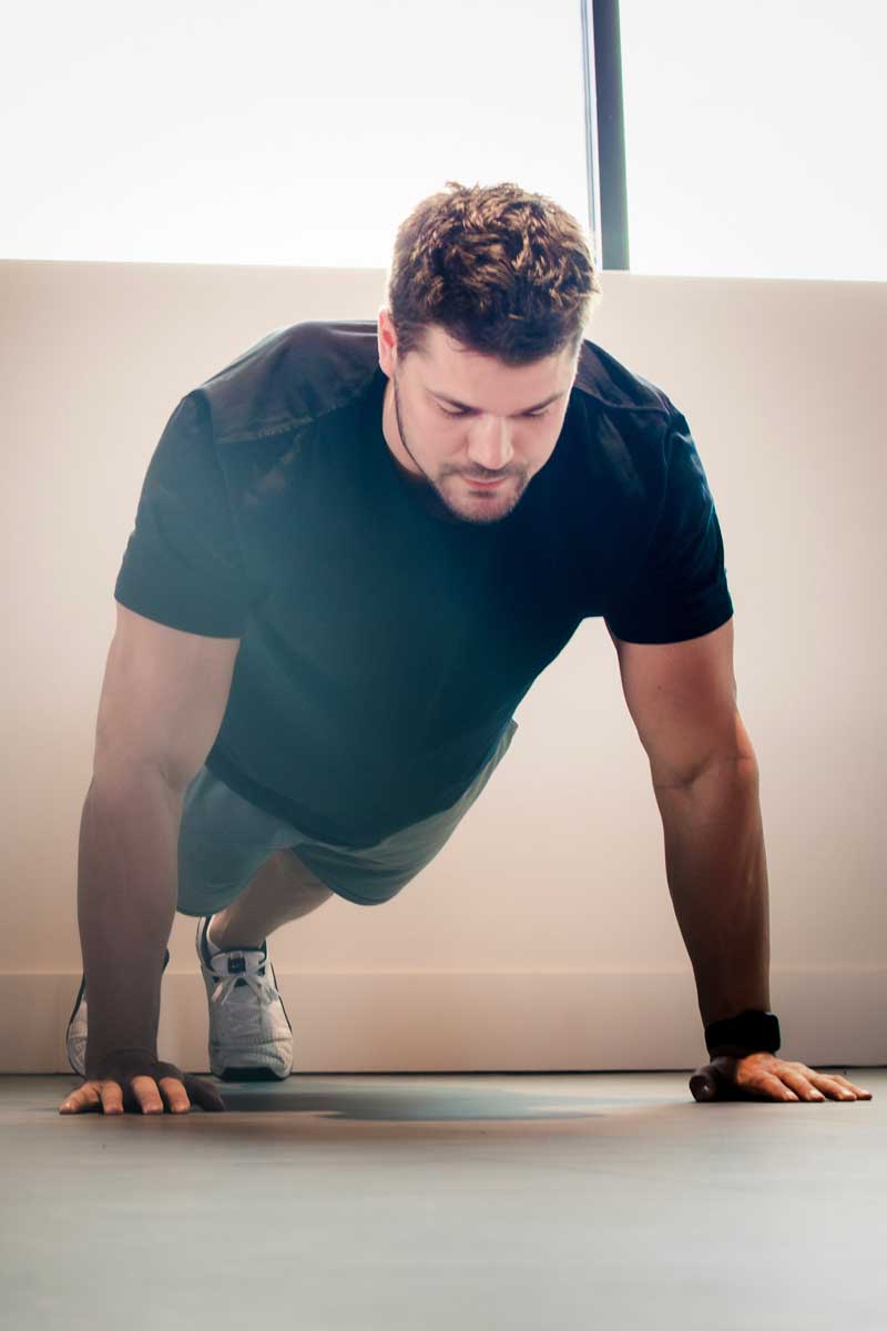 Man doing pushups with cream-colored wall behind him